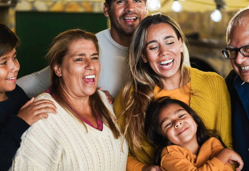 Retrato de una familia latina feliz sonriendo ante la cámara en casa - Enfoque en la cara de la abuela